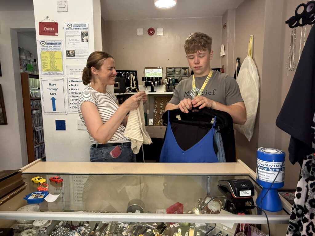 Zoe And Frank sort clothes behind a shop counter